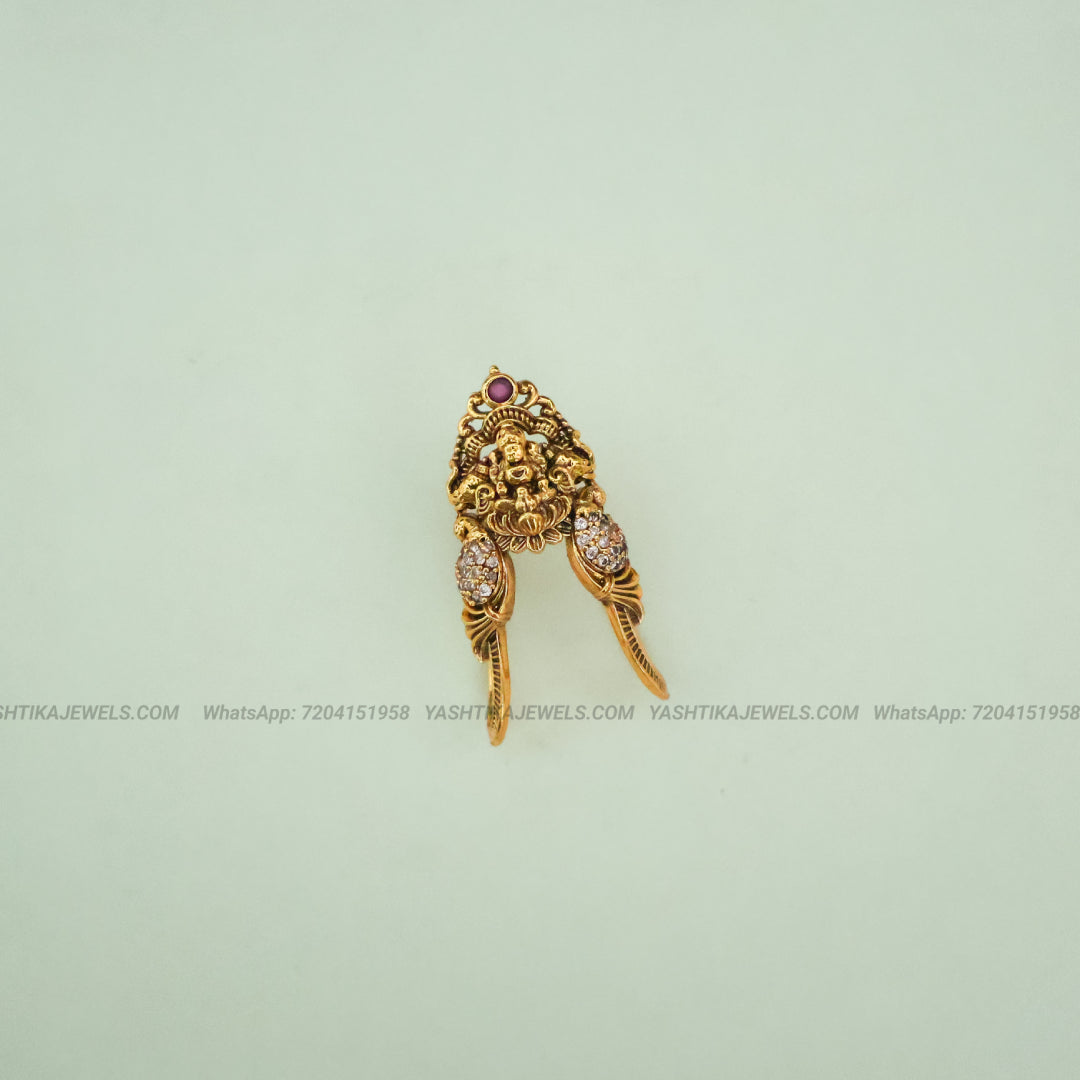 Gold-toned traditional Indian jewelry piece featuring a lion head motif with small red and clear stones, displayed on a pale mint green background.