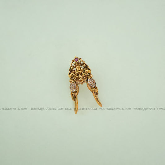 Gold-toned traditional Indian jewelry piece featuring a lion head motif with small red and clear stones, displayed on a pale mint green background.