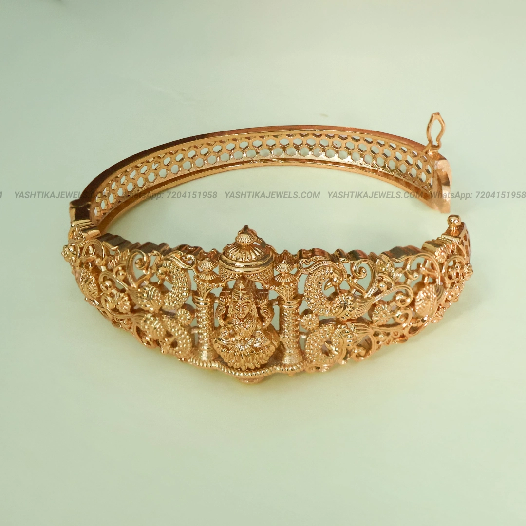 Antique gold-tone Lakshmi temple bracelet featuring a Goddess Lakshmi idol, intricate peacock motifs and traditional ornamental carvings.