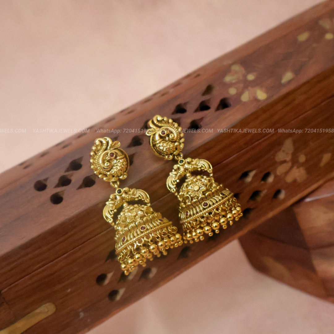 Antique gold-finish jhumka earrings with peacock-inspired studs, Jadua stone accents, intricate gold motifs and hanging gold beads
