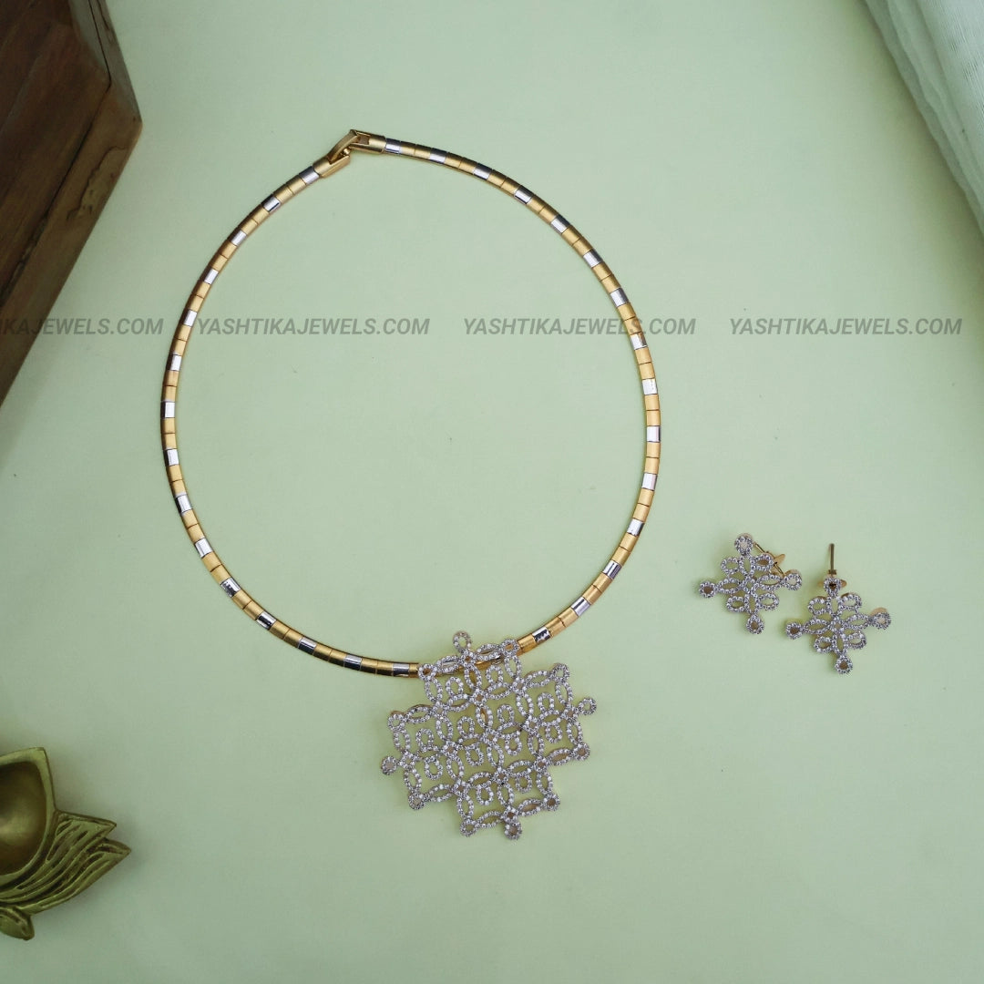 Gold-tone American diamond pendant necklace with geometric lattice design, two-tone chain and matching floral-pattern drop earrings.