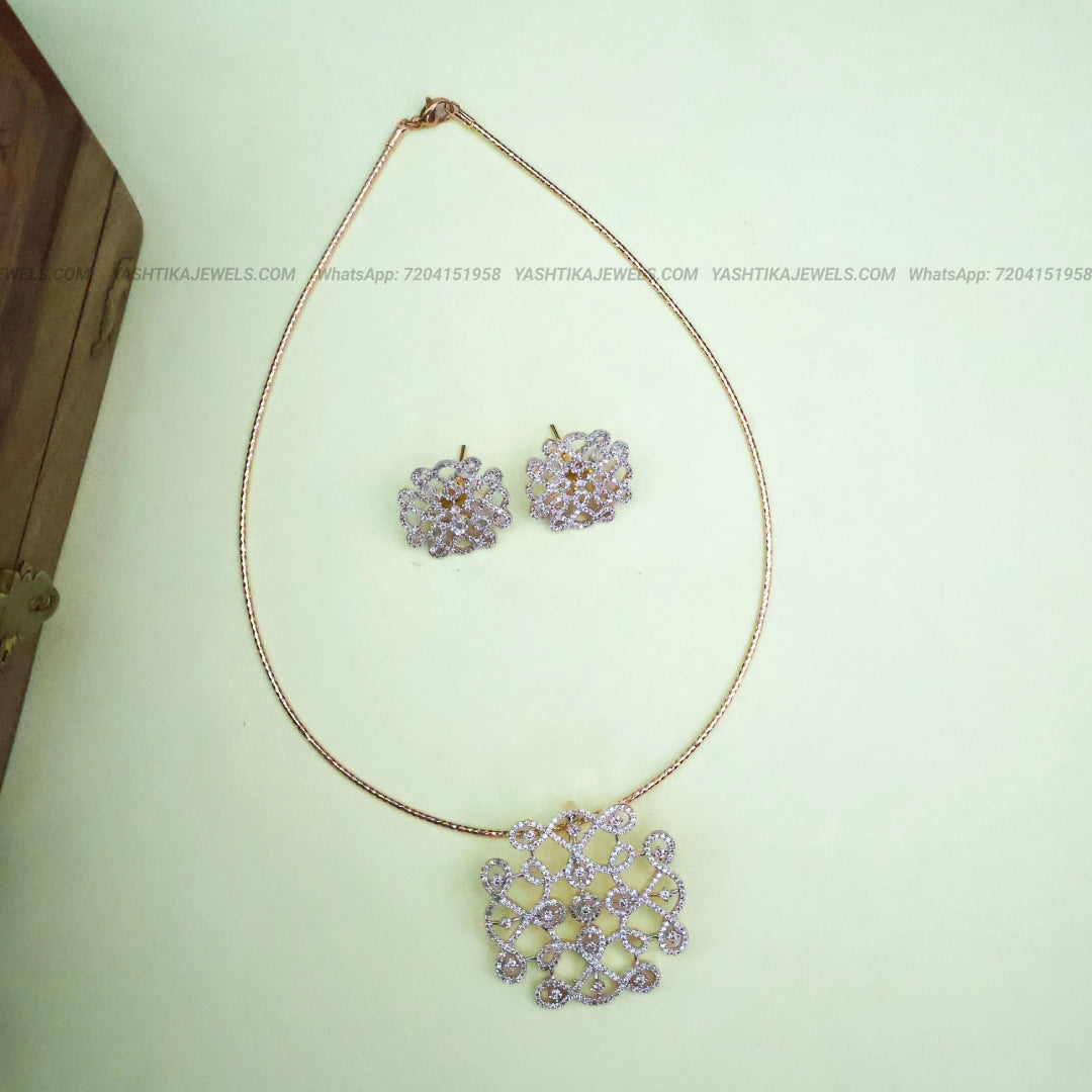 Gold-tone American diamond pendant necklace with an intricate geometric lattice design and matching floral stud earrings.